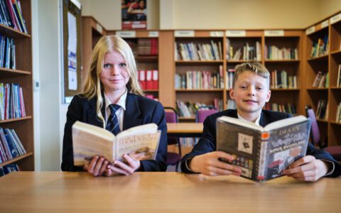 A boy and girl reading books in a library
