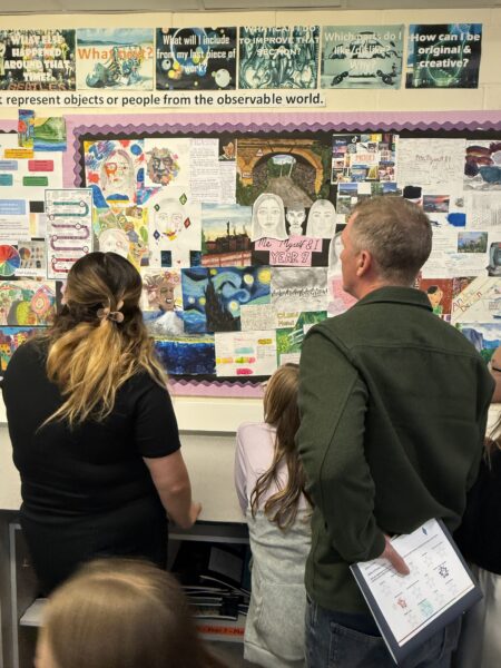 art teacher showing parent and child some artwork