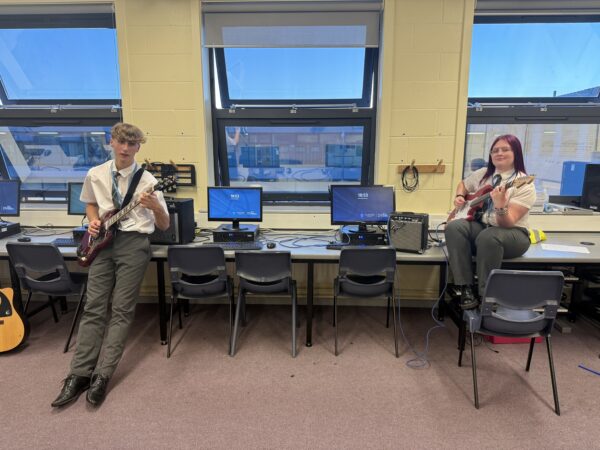 two students playing guitars