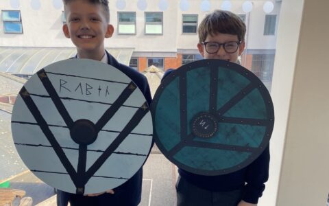 two year 7 boys holding shields